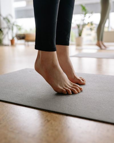 Close-up on feet positioned for a balance exercise on a mat.